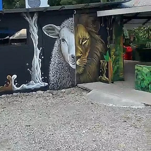 Mural del cordero y el león junto a un chorro de leche en la fachada del local